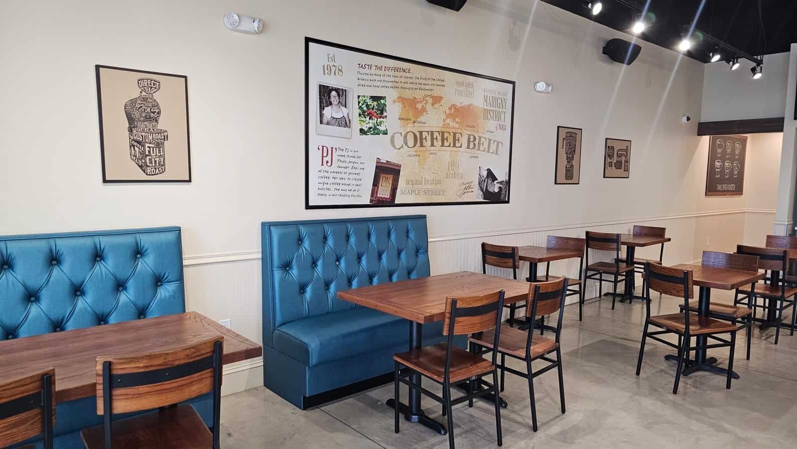 Interior of PJ's Coffee in Middleburg, Florida featuring wooden tables, blue booth seating, and coffee-themed wall art.